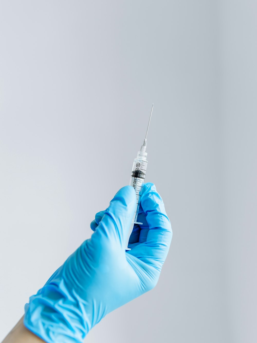Gloved hand holding a syringe